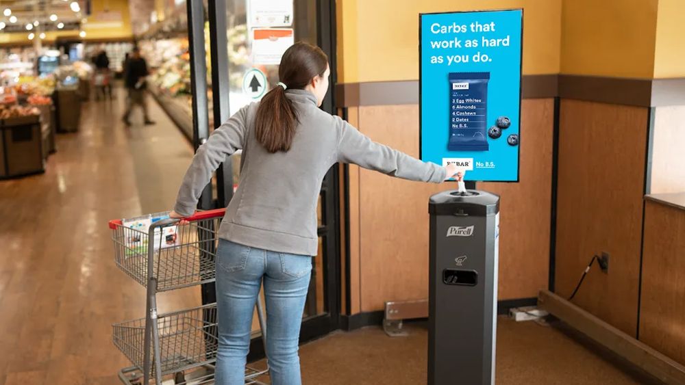 A digital screen above a checkout lane running a dairy brand campaign.